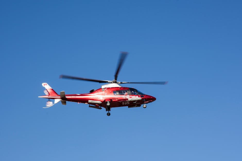 Red helicopter flying against clear blue sky, symbolizing emergency medical rescue.